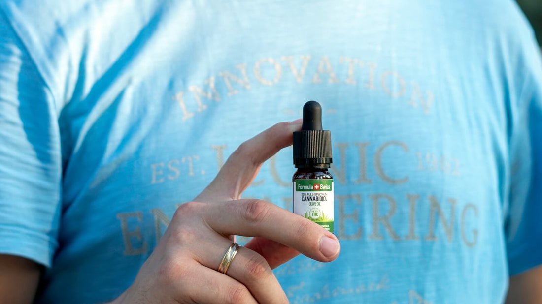 En hånd, der holder en 10 ml flaske Formula Swiss CBD olie i olivenolie